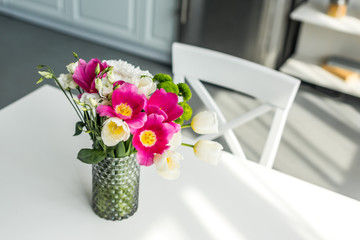 bouquet of beautiful colored flowers on white table at kitchen