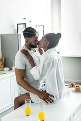 passionate african american couple kissing on kitchen counter at kitchen