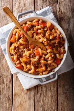 american chop suey, american goulash, with elbow pasta, beef and tomatoes close-up. Vertical top view