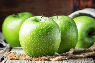 Green apples on vintage wooden background, selective focus