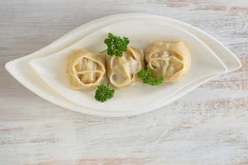 dumpling. Homemade manti dumplings in a white dish  with parsley   on a worn background. Manti . Traditional meat dish.