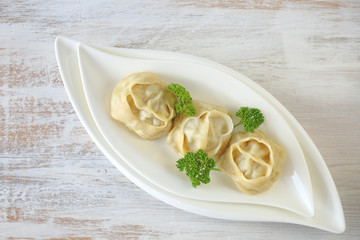 dumpling. Homemade manti dumplings in a white dish  with parsley   on a light  background. Manti . Traditional meat dish.