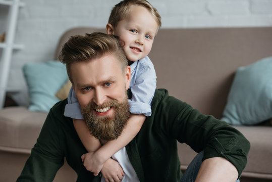 portrait of little son hugging smiling bearded father at home
