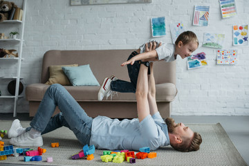 side view of father having fun together with little son while spending time at home