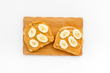 Sandwich with nut butter and banana for breakfast on white background top view