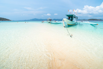 Tropical sand beach with tourists and boats on the Bulog Dos island, Palawan, Philippines