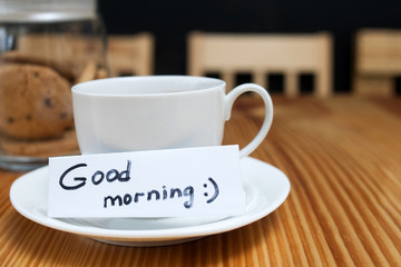 breakfast ritual of coffee and biscuits. white cup with a wishing of good morning on the wooden table