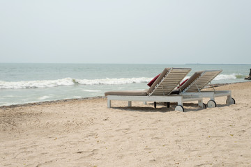Two sun-beds on tropical beach - vacation time