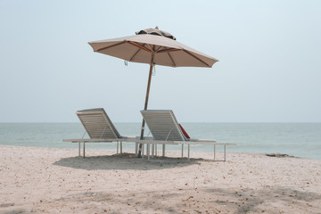 Two sun-beds and umbrella on tropical beach - vacation time