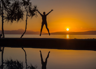 Girl jumping at the waterpool on the beach against the sunset at Balicasag island of Philippines