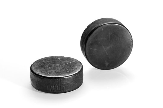 Two hockey pucks on a white background