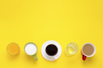 Obraz na płótnie Canvas Group of Drinks in Multicolored Cups, Black Coffee, Coffee with Milk, Yogurt, Just Water, Orange Juice on Yellow Background. Flat lay, top view
