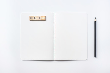 Design concept - Top view of notebook blank page, black pencil and wood cube isolated on white background for mockup
