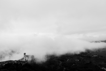 View of St. Francis papal church in Assisi (Umbria, Italy) in the middle of lifting morning fog