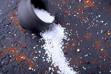 Red spices, salt and pepper on black marble. Black abstract background. Top view.