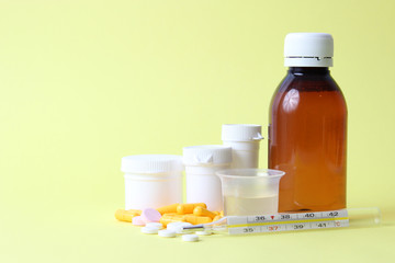 set of different medicines for the treatment of colds on a colored background. thermometer, tablets, syrup. concept of health