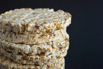 Stack of round rice crispbreads on black paper background. Close up concept of healthy diet with copy space.