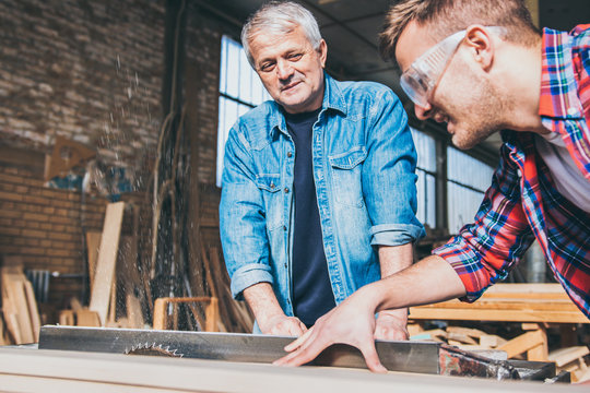 Carpenters using circular saw in workshop