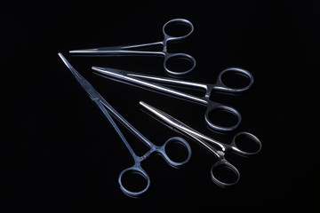 surgical instruments and tools including scalpels, forceps and tweezers on black mirror background.