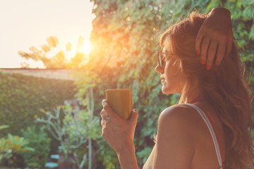 Cute girl enjoying morning coffee on the porch.