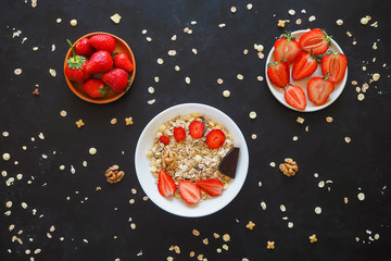 Strawberries and muesli on a black table.