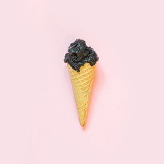 Creative still life of black ice cream in waffle cone on pastel pinkbackground. Spring concept. Top...