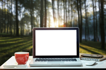Front view of cup and laptop on table in office and background at the sky mountain river and trees front view background. in morning light 
