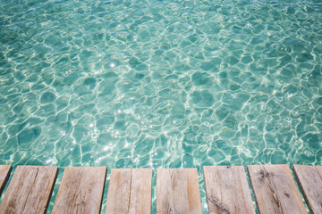 Fototapeta na wymiar Background of wooden deck and blue water see. Mallorca, Spain. Top view. 