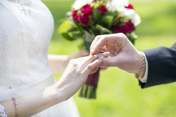 groom dresses a gold ring on a finger of the bride on a wedding day