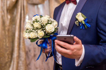 the groom is holding a phone and a bouquet of the bride