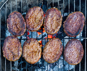 Hamburgers cooked on barbecue grill.