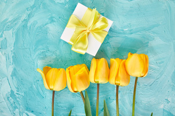 Gift box with yellow ribbon near tulip