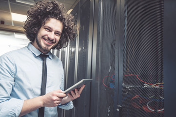 Fototapeta premium male technician inspecting and working on servers in server room