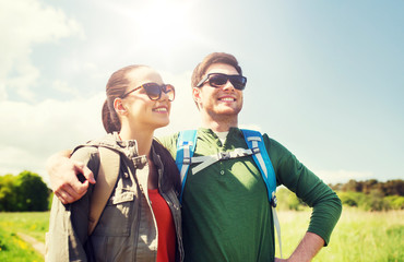 travel, hiking, backpacking, tourism and people concept - happy couple with backpacks hugging and walking outdoors