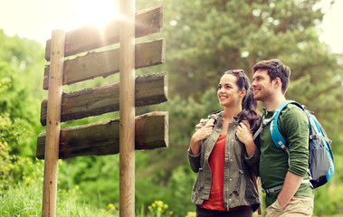 adventure, travel, tourism, hike and people concept - smiling couple with backpacks looking at...