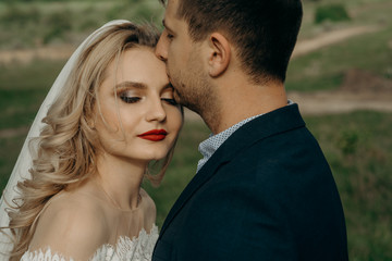 Naklejka premium Newlyweds couple in love. Romantic wedding moment, relationships. Bride and groom kisses tenderly, beautiful pictures. guys enjoy. Sexy kissing stylish couple of lovers close up portrait.