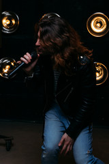 Fototapeta na wymiar Brutal singer with long hair, with microphone on the stage