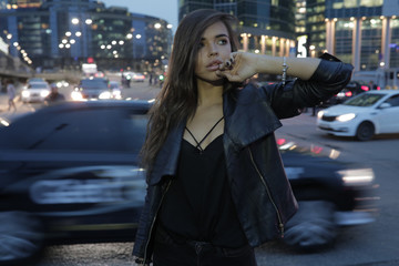 Fototapeta premium Beautiful woman on a background of a night city and passing cars.