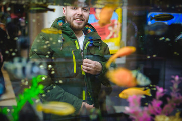 Obraz premium man looks at tropical fish in aquarium
