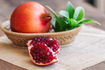 Sweet and juicy Indian red pomegranate in wooden basket and on wood table in side view with copy space for background. Delicious and healthy fruit which have vitamin c and antioxidant for good skin.