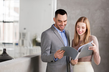 business, people and corporate concept - happy smiling businesswoman and businessman with folder at office