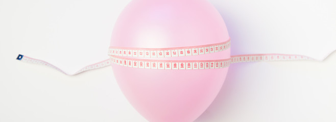 Balloon tied measuring tape on white background. Weight loss, slim body, healthy lifestyle concept. The waist measurement.