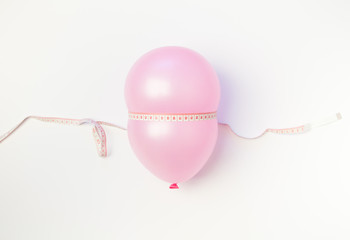 Balloon tied measuring tape on white background. Weight loss, slim body, healthy lifestyle concept....