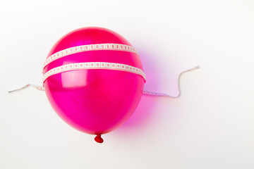 Balloon tied measuring tape on white background. Weight loss, slim body, healthy lifestyle concept....