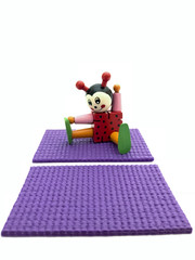 A ladybug sits on a fitness mat next to another empty purple yoga mat in the foreground