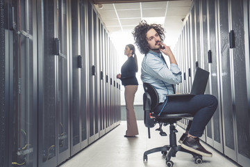 male technician inspecting and working on servers in server room