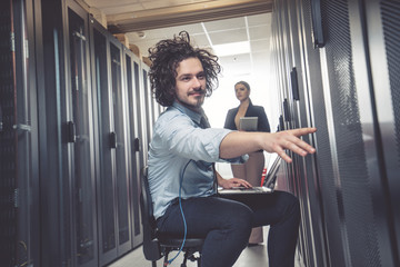 male technician inspecting and working on servers in server room