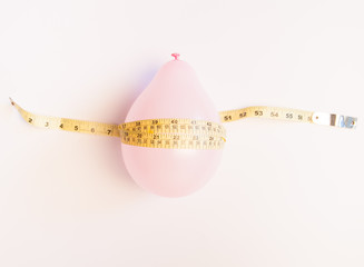 Balloon tied measuring tape on white background. Weight loss, slim body, healthy lifestyle concept. The waist measurement.