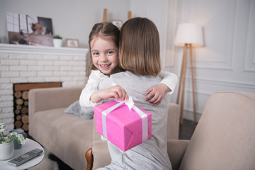 My gift. Charming happy girl holding her gift and hugging her mom
