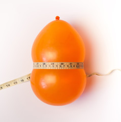 Balloon tied measuring tape on white background. Weight loss, slim body, healthy lifestyle concept. The waist measurement.